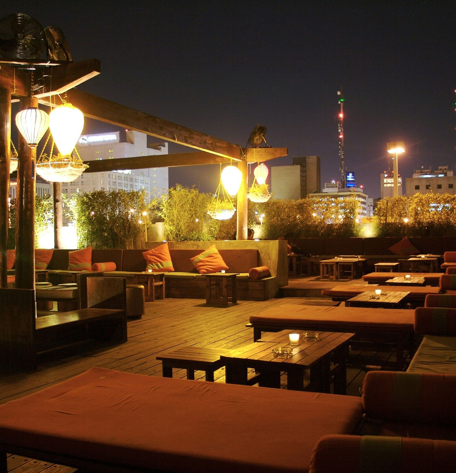 an image of rooftop lounge space surrounded by plants illuminating yellow lights