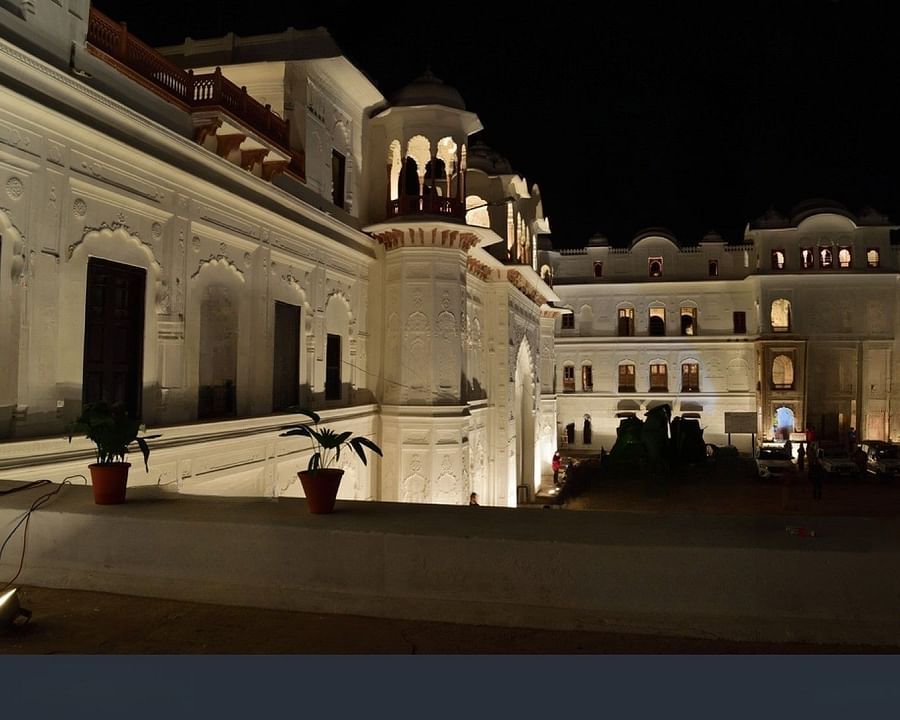 A large, illuminated palace with multiple towers and balconies, surrounded by a courtyard.