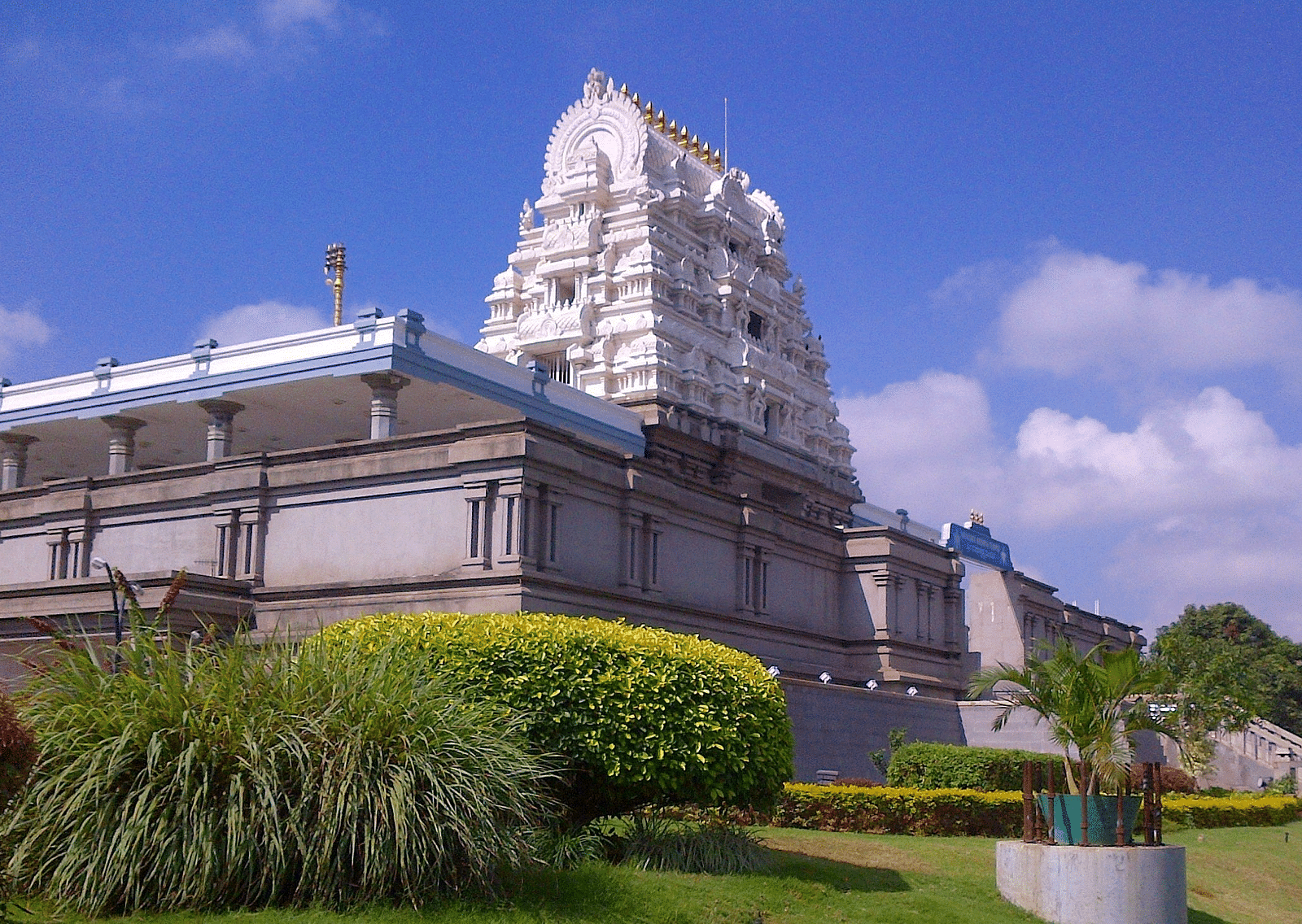 An overview of ISKCON Temple with a lawn area in the foreground and blue sky in the background.