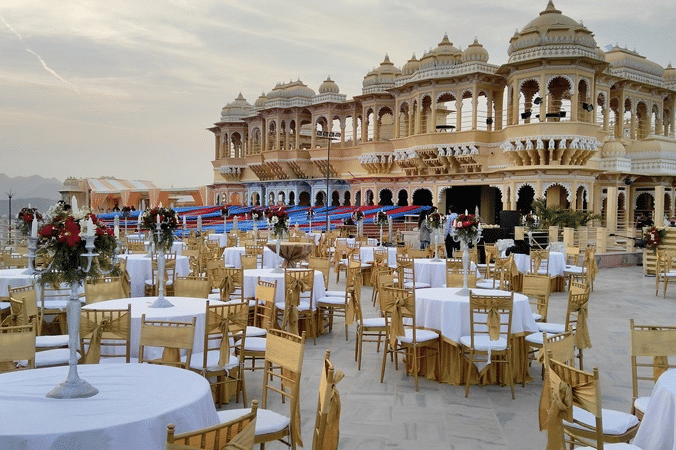 The expansive Square Terrace at Chunda Palace, Udaipur, meticulously arranged with numerous round banquet tables and chairs for an event.