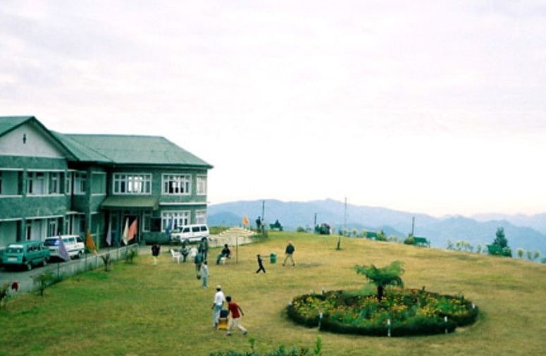 A building with a large lawn with mountains in the backdrop