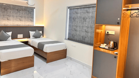 Bedroom with two single beds, a wooden wardrobe, wall-mounted air conditioning unit, and tiled flooring | Hotel Aurora Bliss