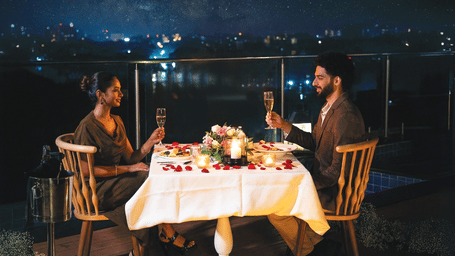 Promotional creative for A Valentine Under the Stars featuring a romantic candlelit dining setup under the night sky for Valentine’s Day.