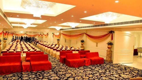 An elegant  banquet hall, with ornate golden ceiling details, red velvet seating, patterned carpeting, and opulent interior design at a luxury hotel in Lucknow - Clarks Avadh, Lucknow.