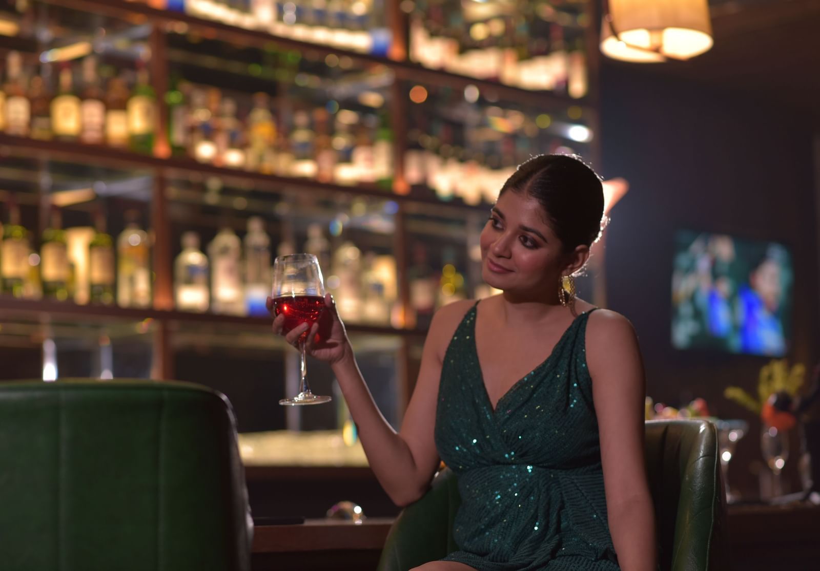 A woman at the Grand Bar raising her glass, enjoying the evening - Polo Hotel Agartala