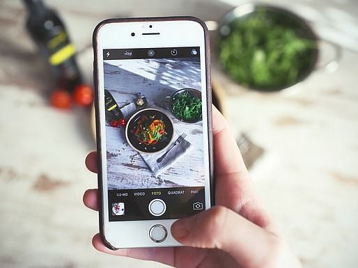 Person using a smartphone to capture an outdoor food photo.