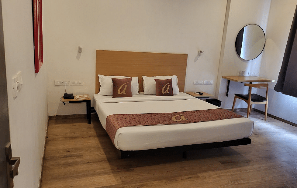 A cosy hotel room with a neatly made double bed, soft lighting, and a large window with dark curtains - Astra Hotels & Suites, Sarjapura