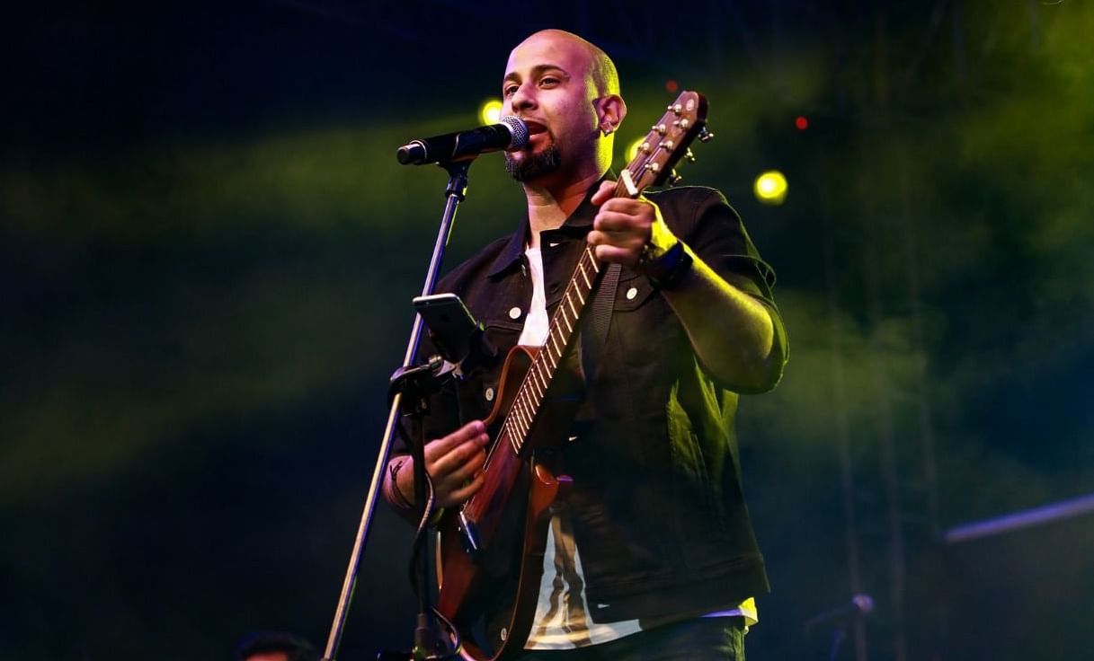 A musician wearing a stylish vest passionately plays a guitar on stage