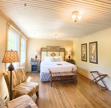 full view image of a bedroom with modern furnishings featuring a double bed along with two cushioned armchairs - Historic Tapoco Lodge