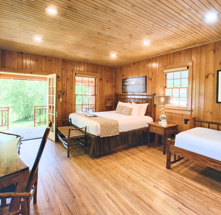 a room featuring a huge entrance to the room with wooden interiors featuring a double bed and a work desk and chair - Historic Tapoco Lodge