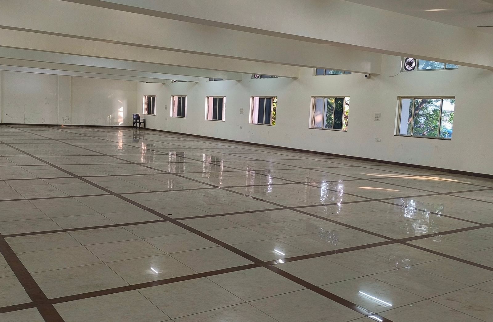 An expansive, vacant banquet hall at BNGV Grandeur Hotel and Banquets with a shiny floor, highlighting its potential for large gatherings.