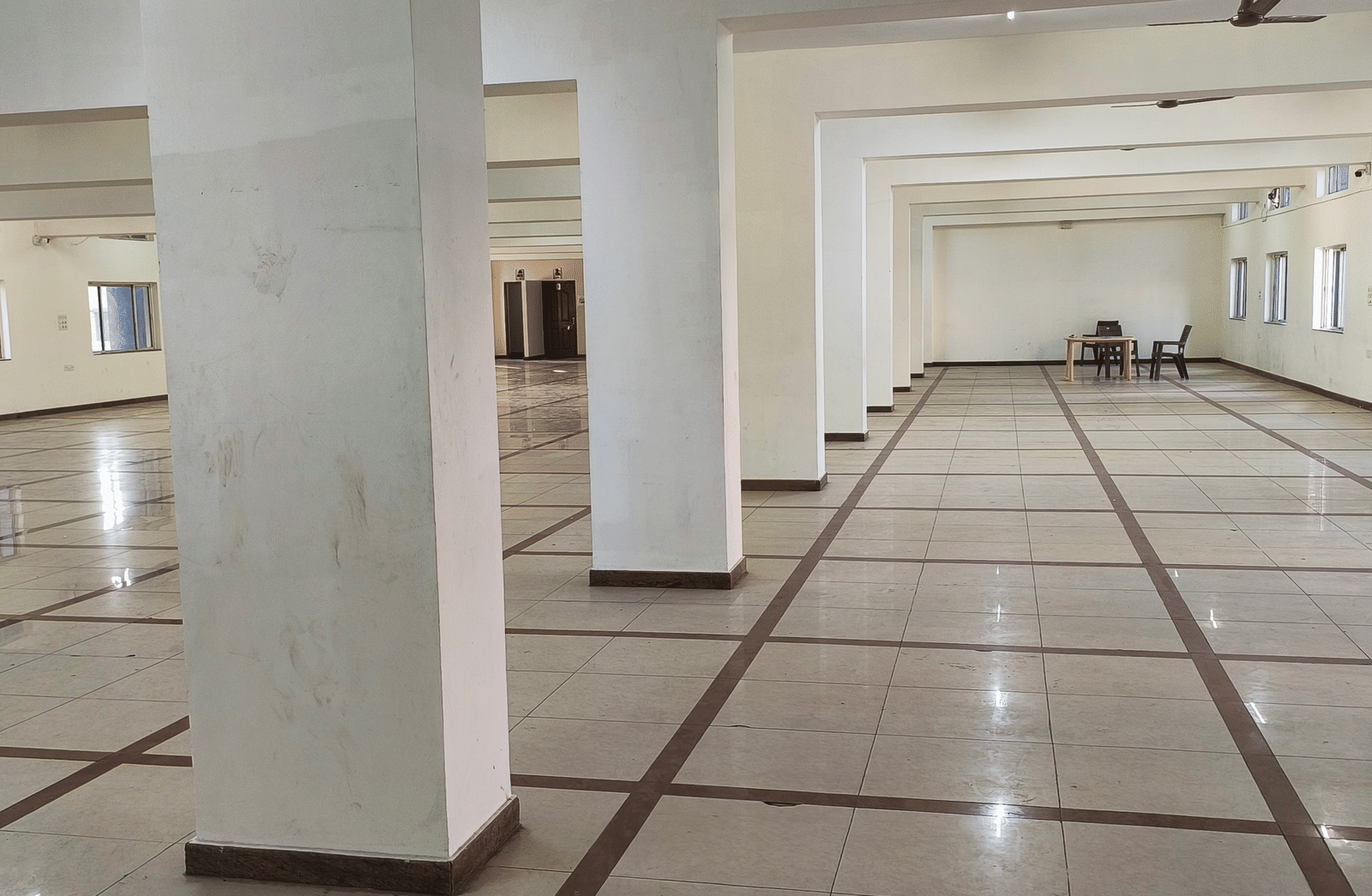 A bright, empty banquet hall within BNGV Grandeur Hotel and Banquets, showcasing the hall's clean and open design.