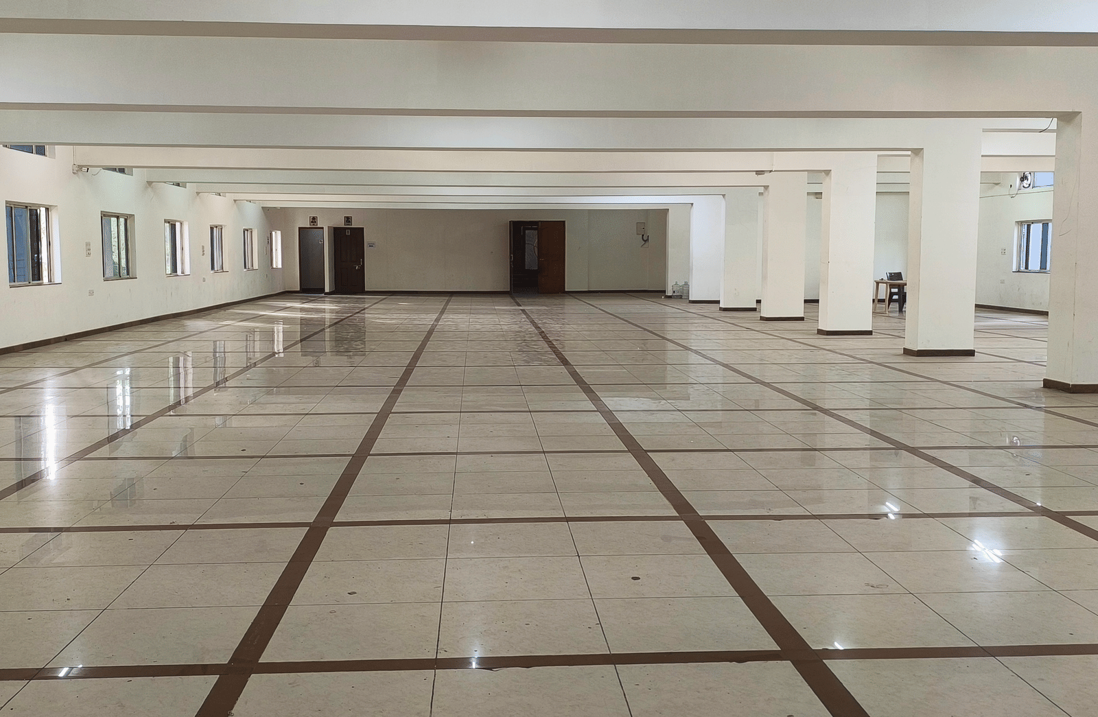 A vast, empty banquet hall in BNGV Grandeur Hotel and Banquets with a polished marble floor, ready for a large event.