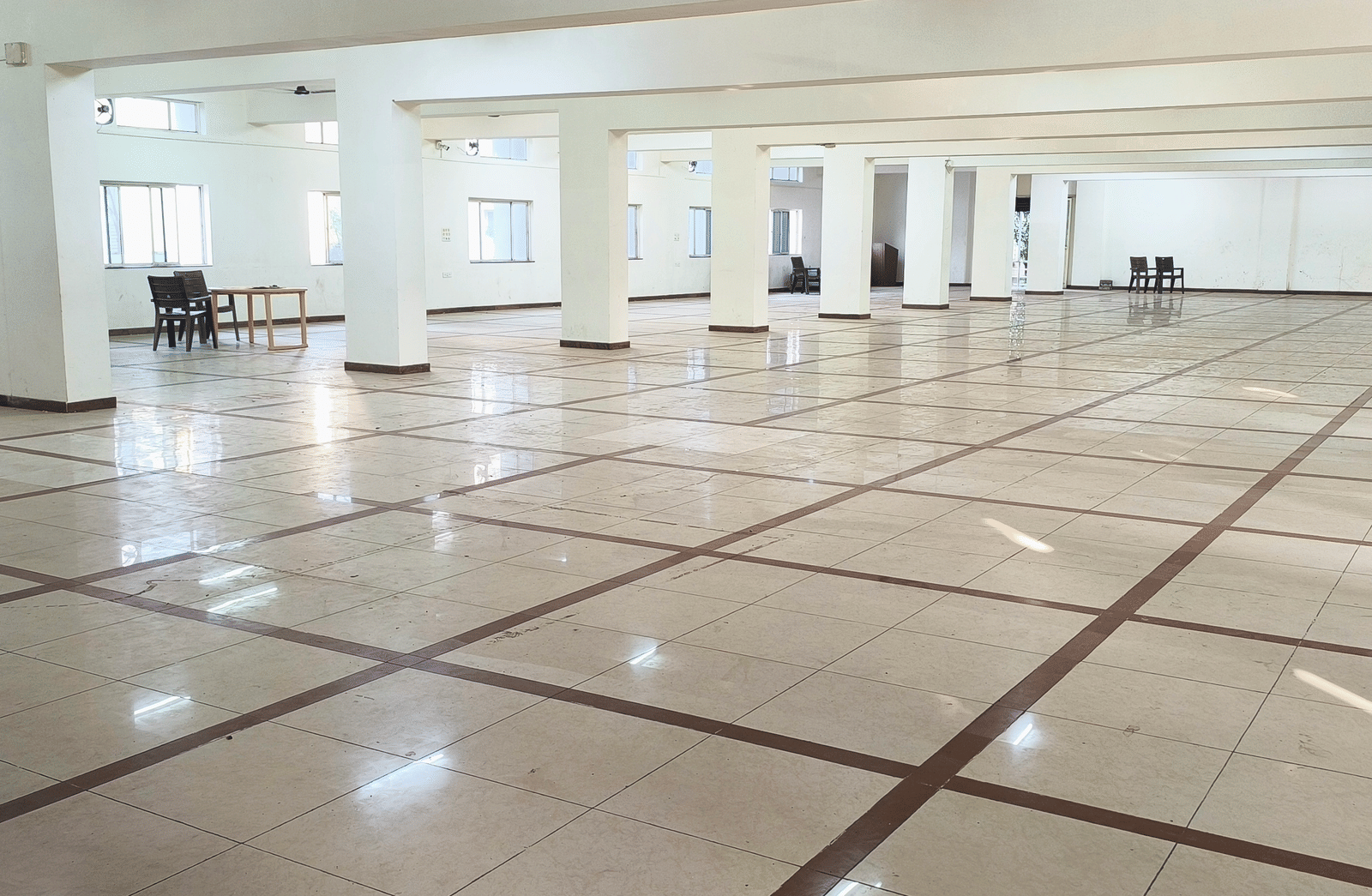 A long view of a spacious, empty banquet hall at BNGV Grandeur Hotel and Banquets, showing the extensive floor space and architectural details.