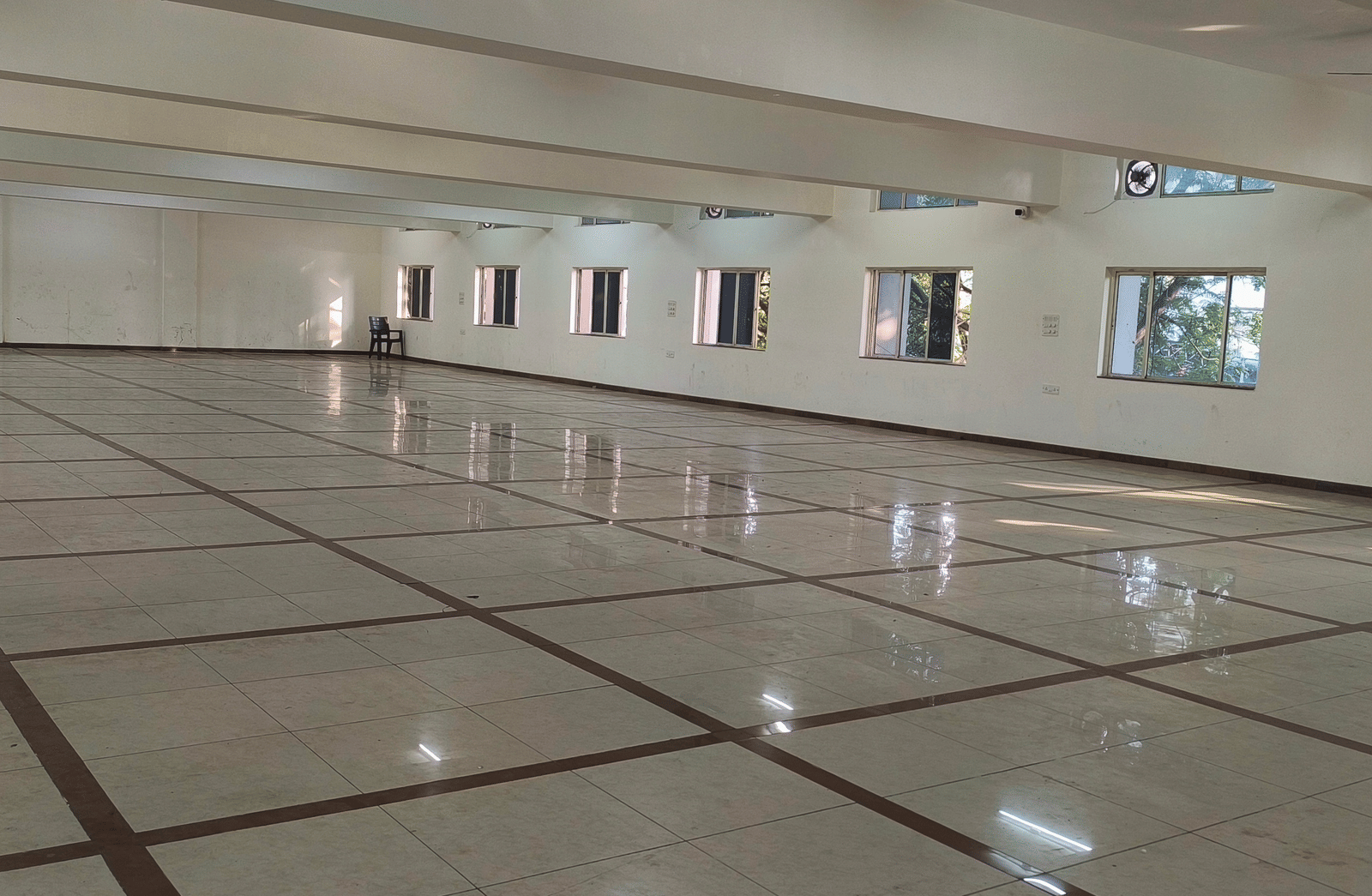 An expansive, vacant banquet hall at BNGV Grandeur Hotel and Banquets with a shiny floor, highlighting its potential for large gatherings.