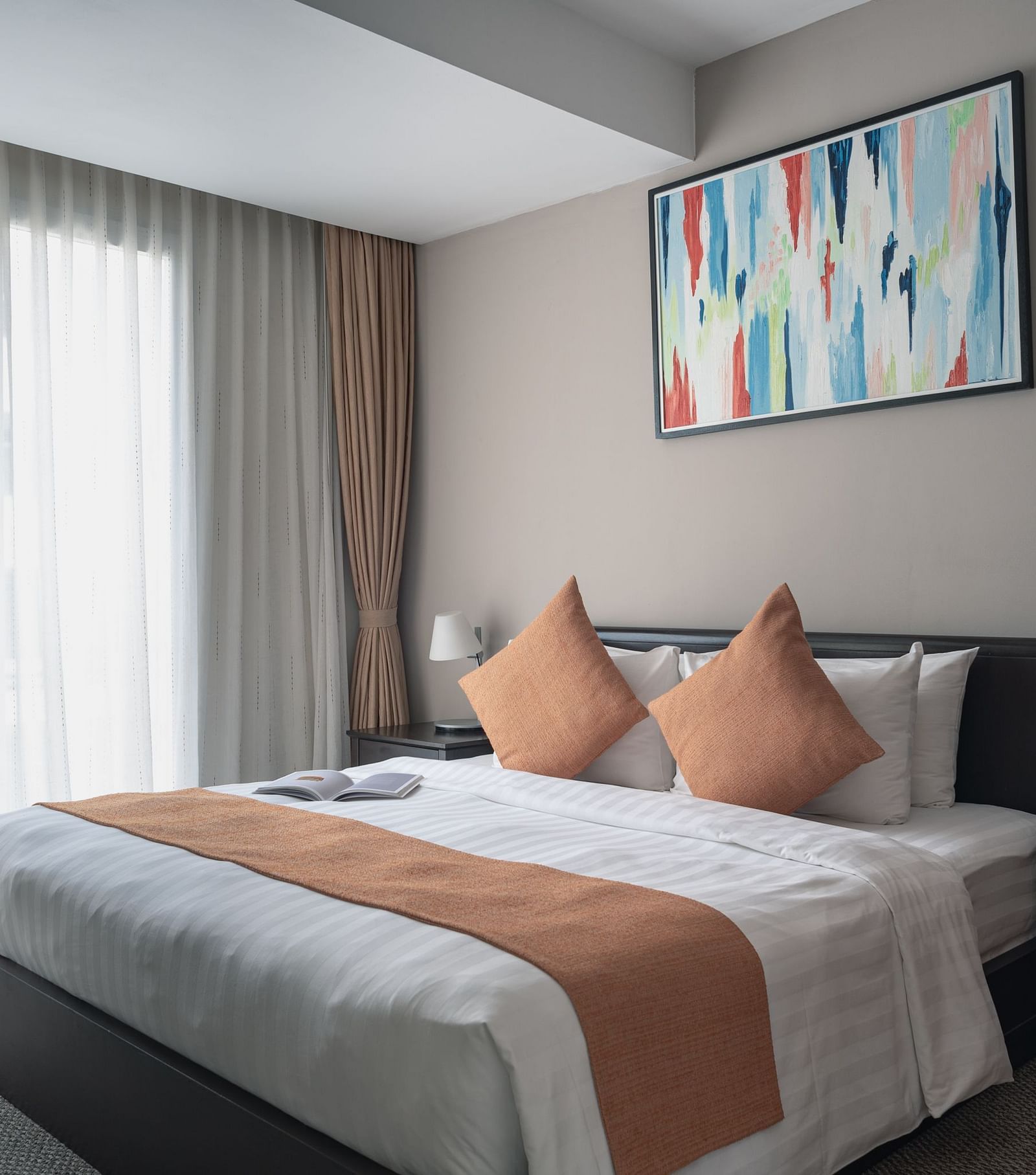 A bedroom with a large bed, a nightstand, and a piece of art on the wall | Three-bedroom Suite | Central Mansions, Phnom Penh