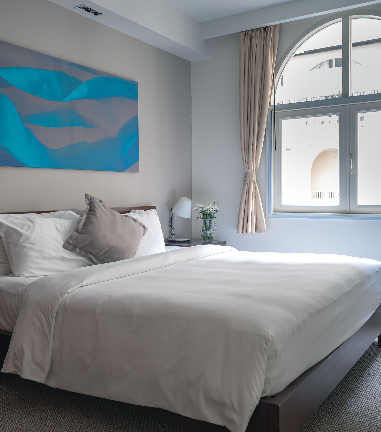 A bedroom with a large bed, a nightstand, and a painting on the wall | Two-bedroom Suite | Central Mansions, Phnom Penh