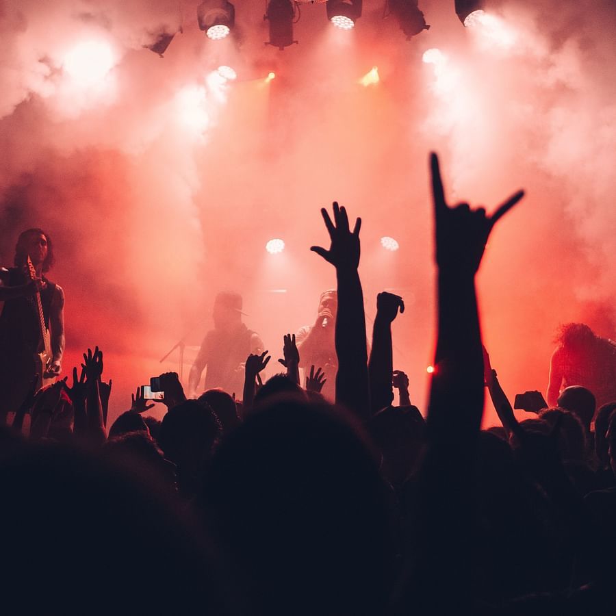 people enjoying at a nightclub with coloured smoke on the stage