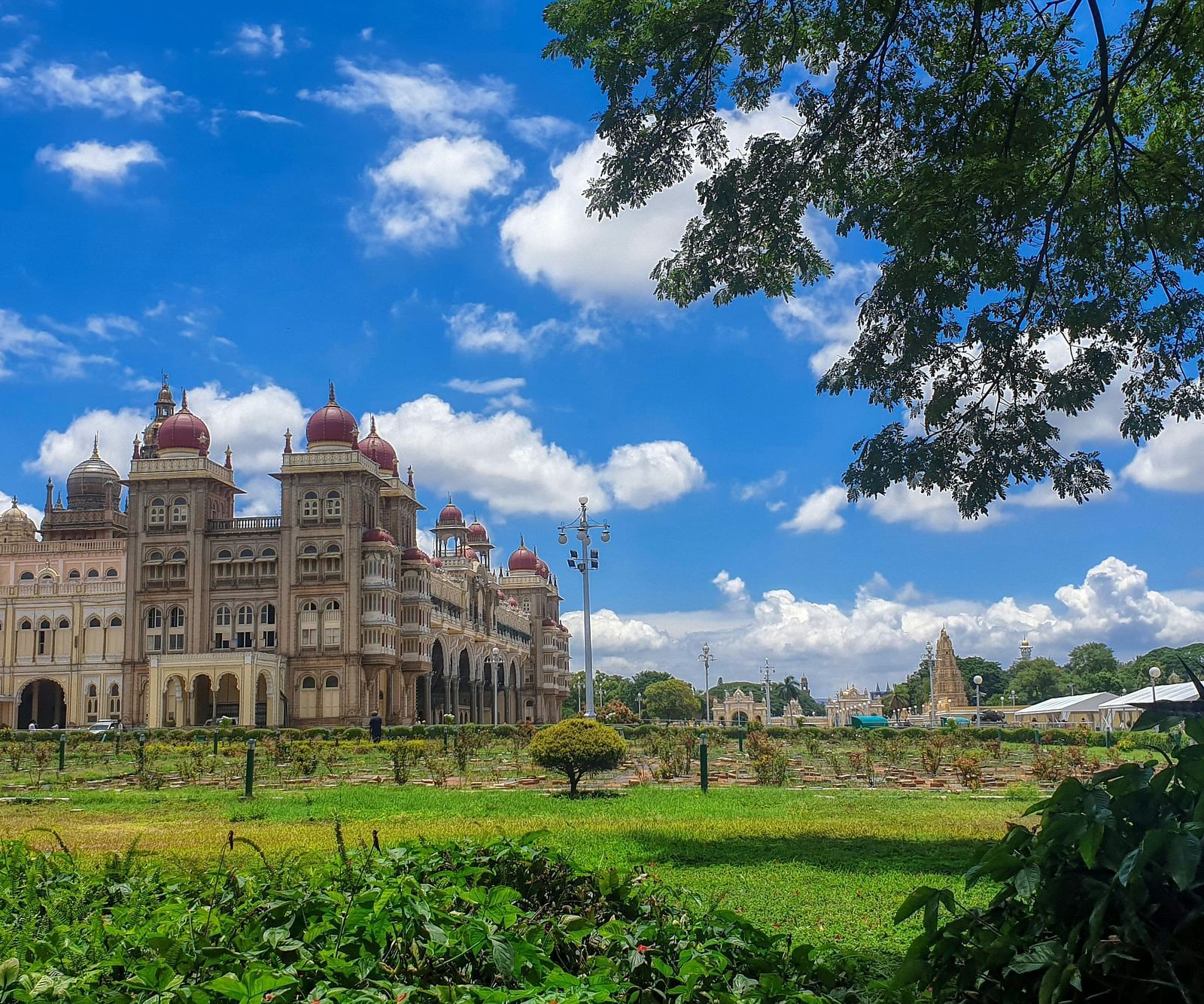 A far out view of the mysore palace with a manicured garden in the foreground