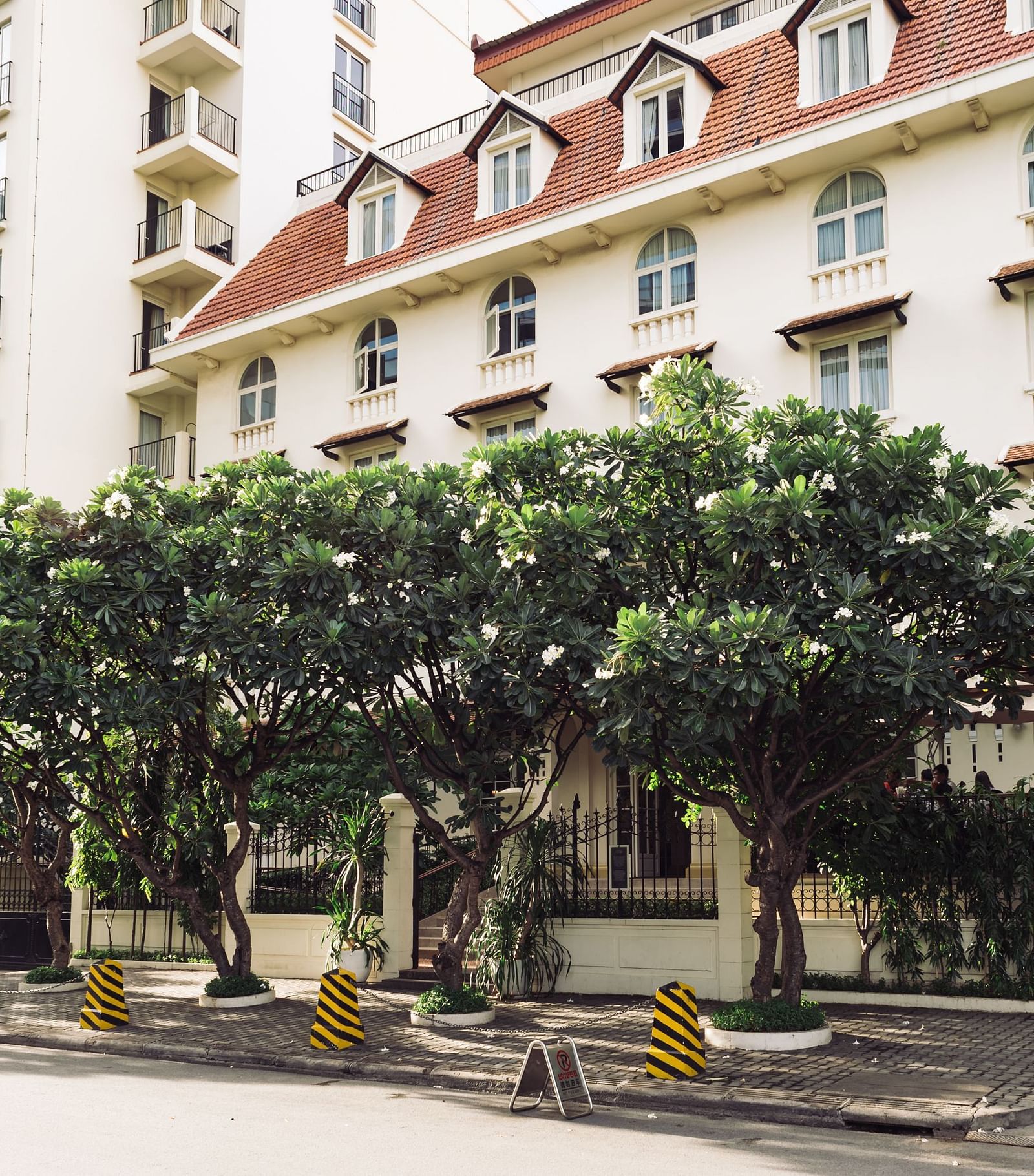 A street view of a multi-storey building with trees lining the road | Central Mansions, Phnom Penh