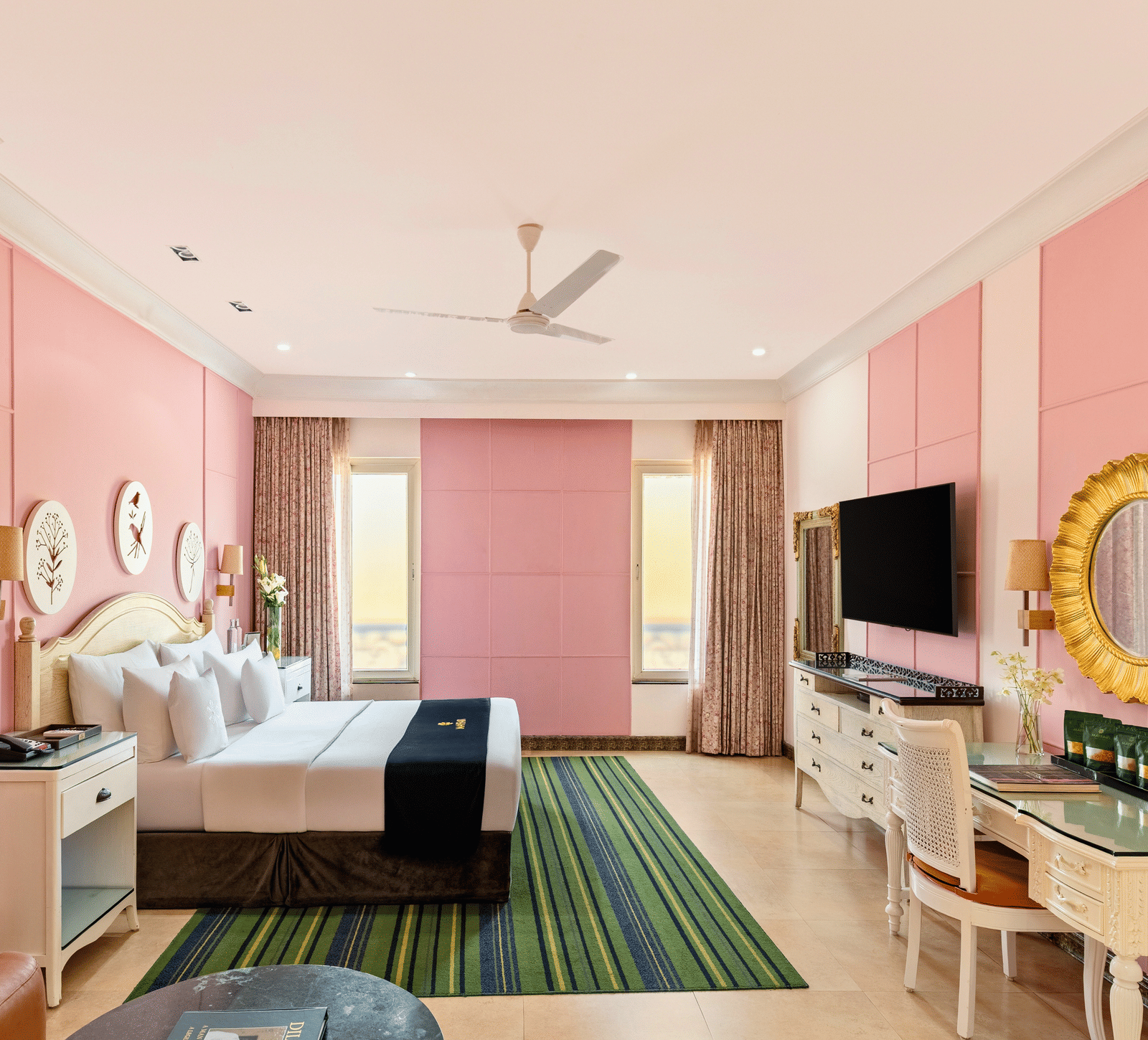 Family room with a king bed, a writing desk, an armchair, a wall-mounted television and curtained windows at MAYFAIR Palm Beach Resort, Gopalpur-on-Sea.