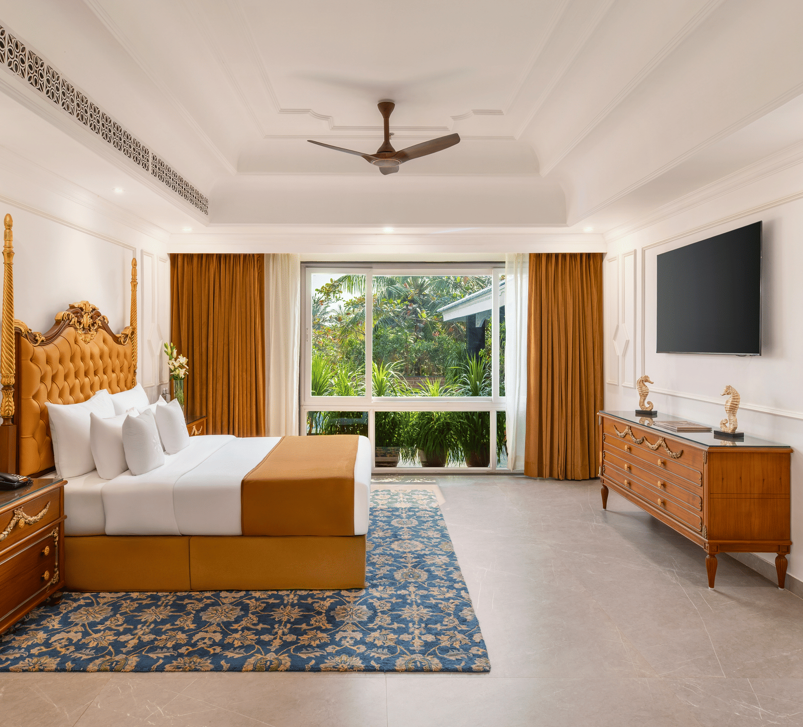 Honeymoon villa with a carved wooden four-poster bed, a dresser, a wall-mounted television and a garden-facing window at MAYFAIR Palm Beach Resort, Gopalpur-on-Sea.
