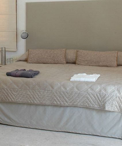 A bedroom with a low bed, cushions, and a small decorative bowl - Shreyas Retreat