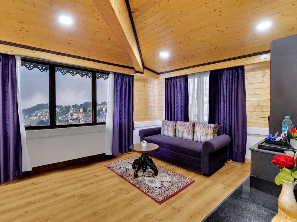 An image of a room with a sofa, a round table and amenities provided by the hotel - Sumitel Darjeeling