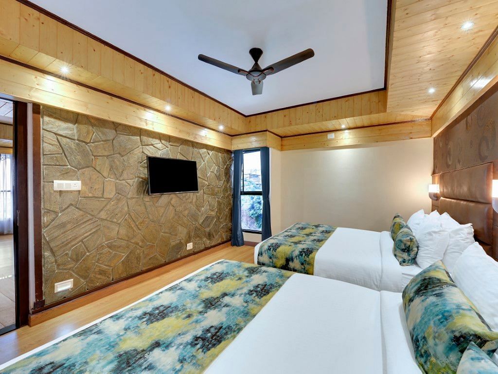 An image of Sumitel Queensyard premium room with king size bed, tv, ceiling fan, and minimal decoration