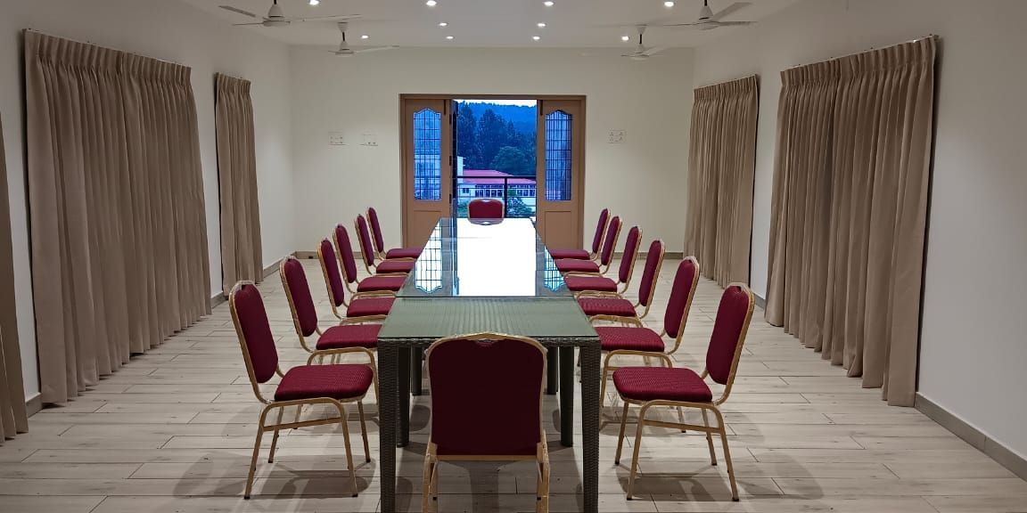 Front-view shot of the Green Park hall with chairs and tables arranged in boardroom setting at WOW Naturefull Resorts.