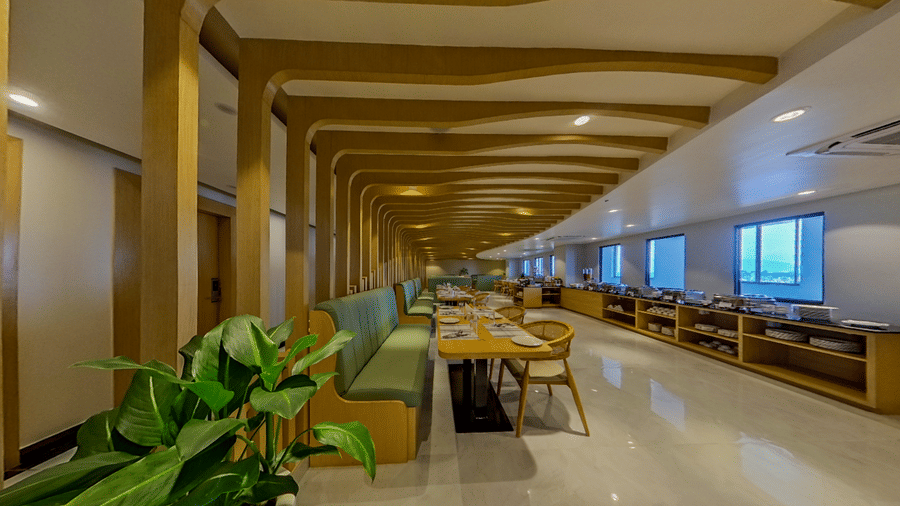 A side view of a dining area with chairs, buffet counters, and plants | Lords CBC Plaza, Chitwan