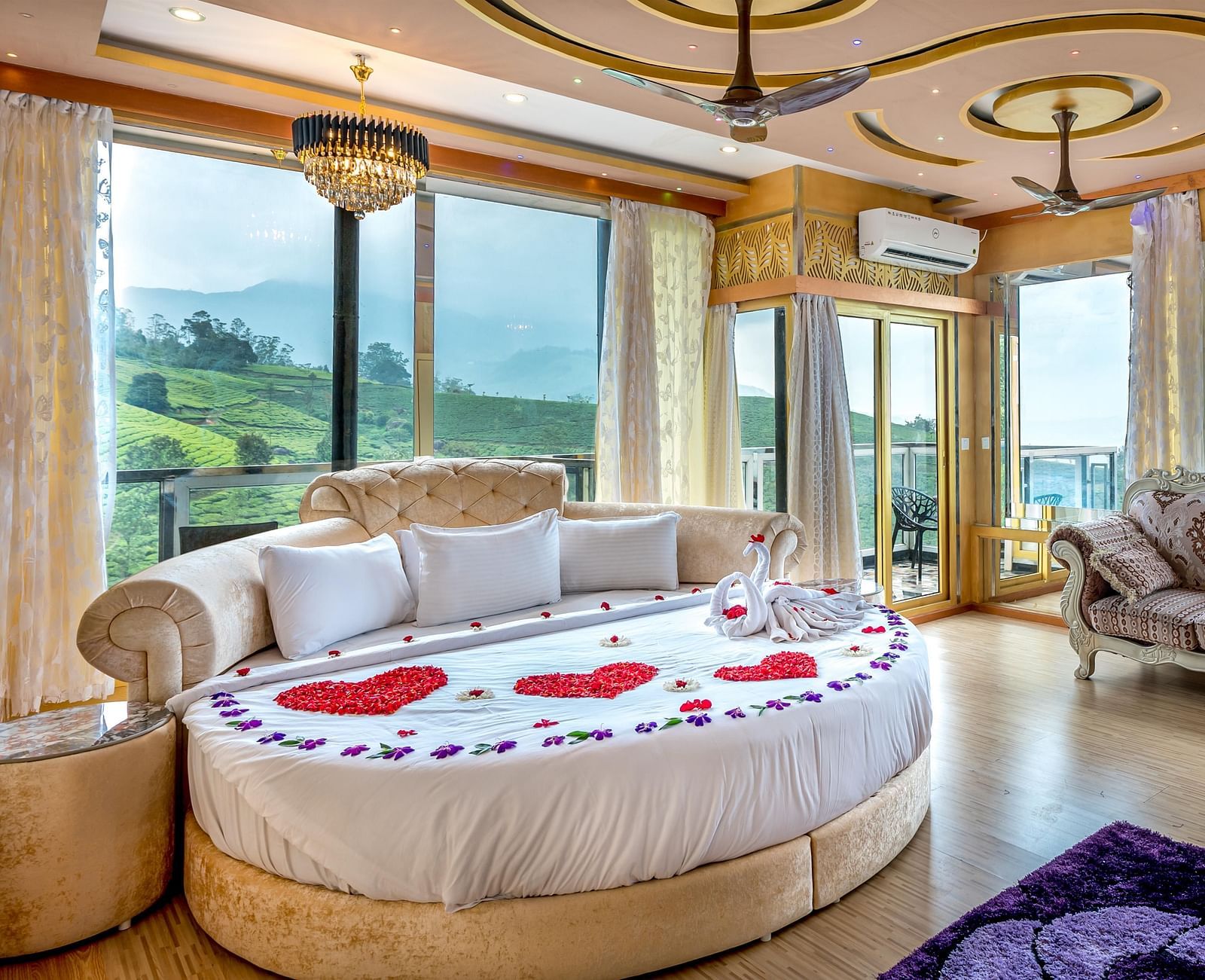 An image of a bedroom with round bed with cushions and next to it is a stylish sofa and the entire room is filled with natural light -  Parakkat hotel & resorts