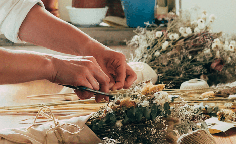 a close up shot of a person typing a bunch of flowers with a jute string