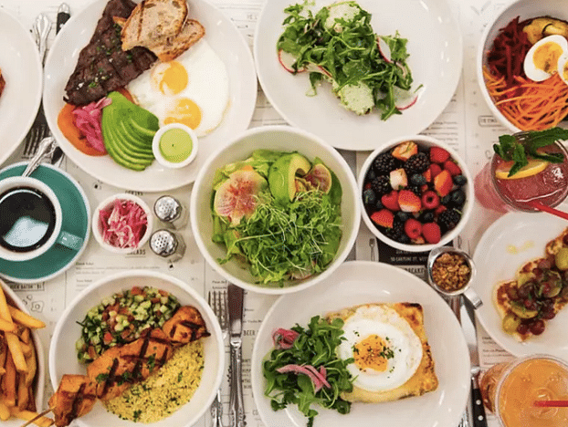  Top view of a spread of food with various dishes and edibles on white plates. 