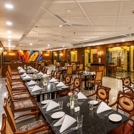 1914 Pan Asian Restaurant at MAYFAIR Palm Beach Resort, Gopalpur-on-Sea featuring several sets of dining table and chairs, and at one corner there is a reception.