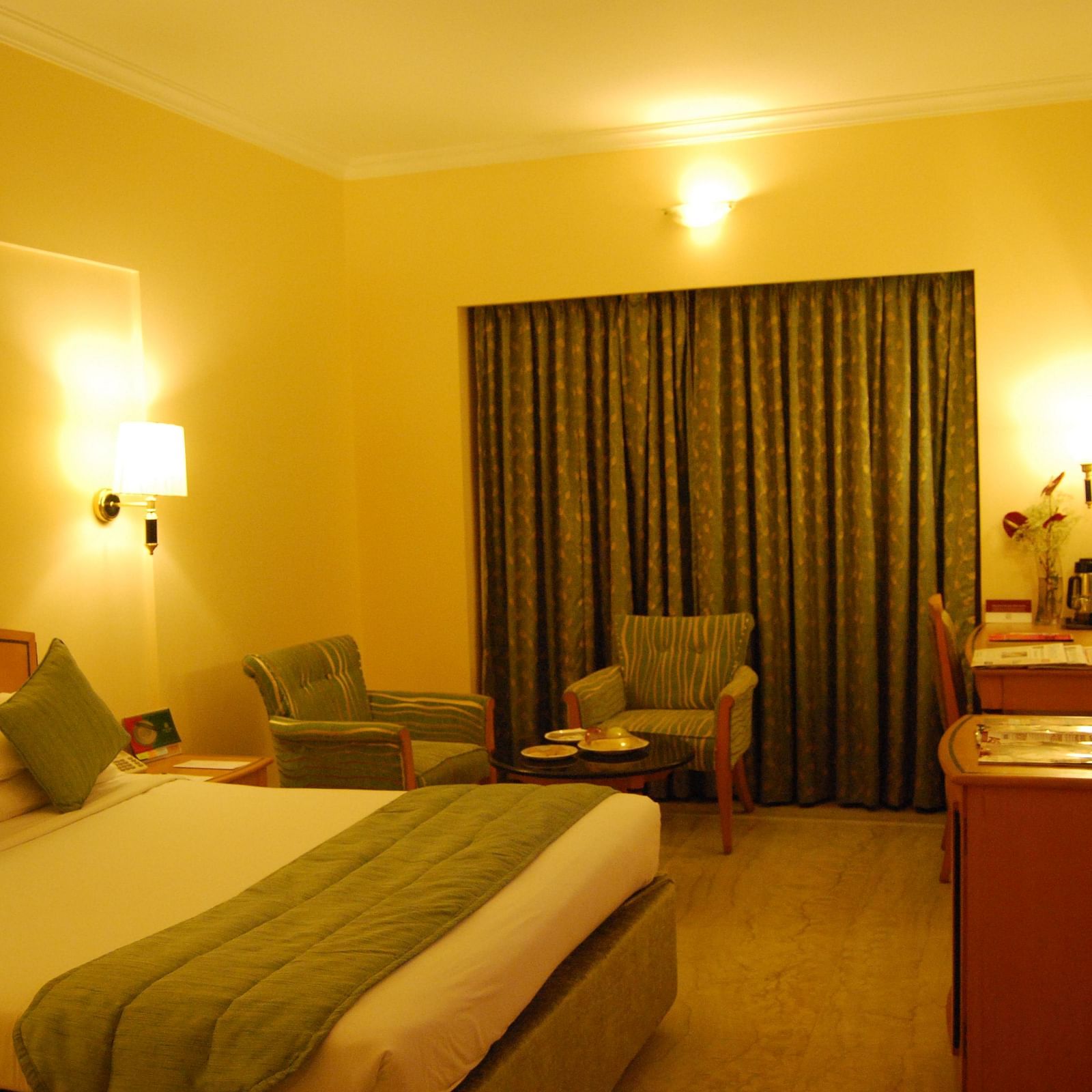 A photo showing a room with bright lights where a large bed, two chairs, and a flat screen TV are visible.