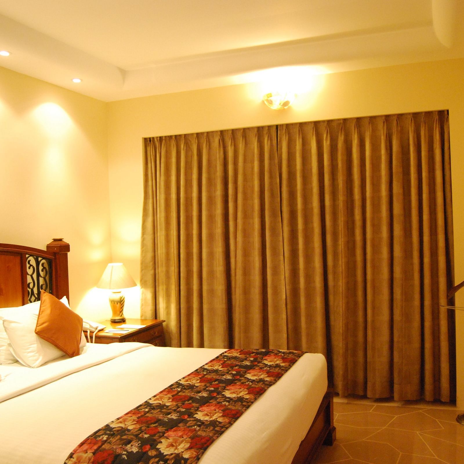 A king bed with a large mattress and cushions, facing a flatscreen TV in a well lit room