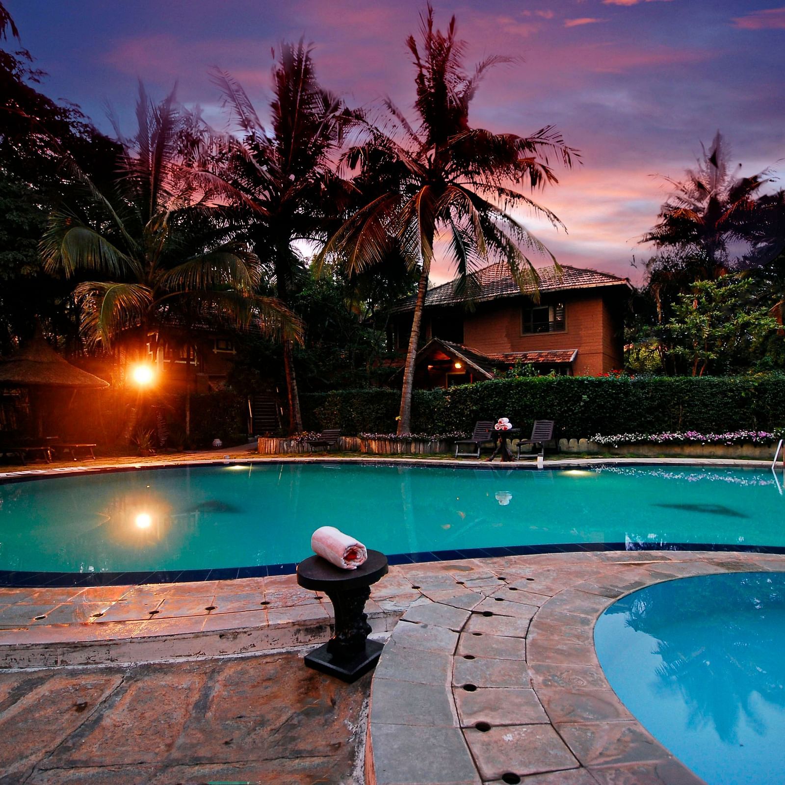 An overview of a swimming pool in the night - Hoysala Village Resort, Hassan.