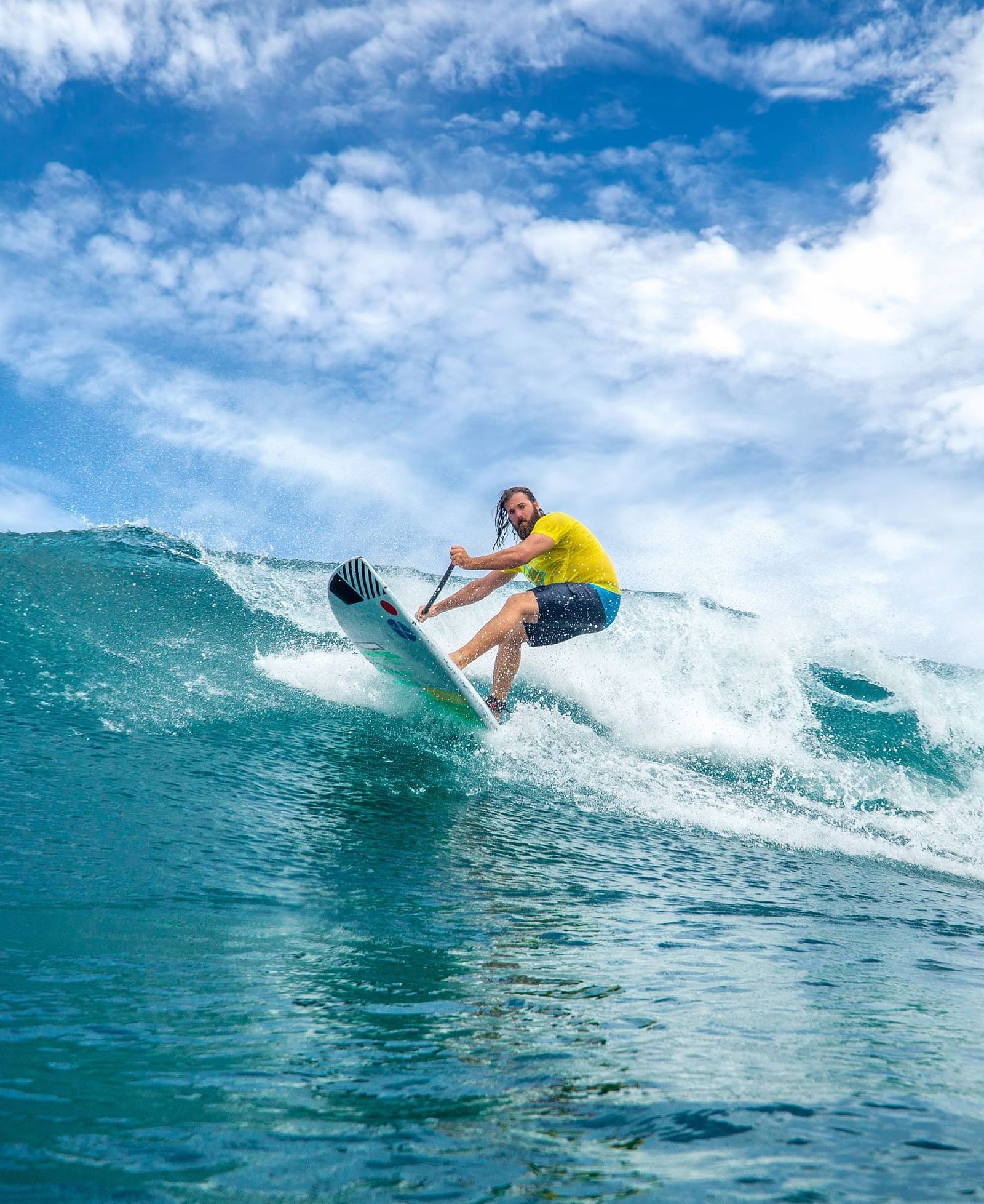 A surfer riding a powerful ocean wave, leaning forward on the surfboard while maintaining balance against the rushing water | Abaco Inn