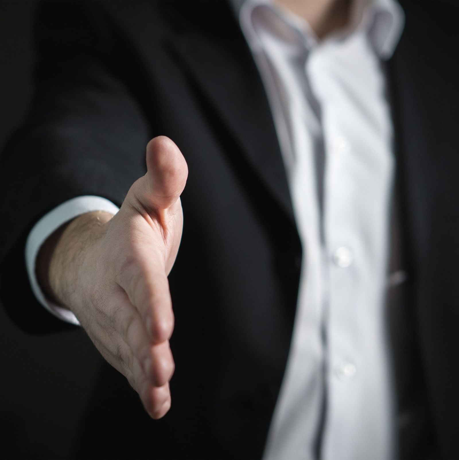 image of a man dressed in business formals extending his hand for a handshake