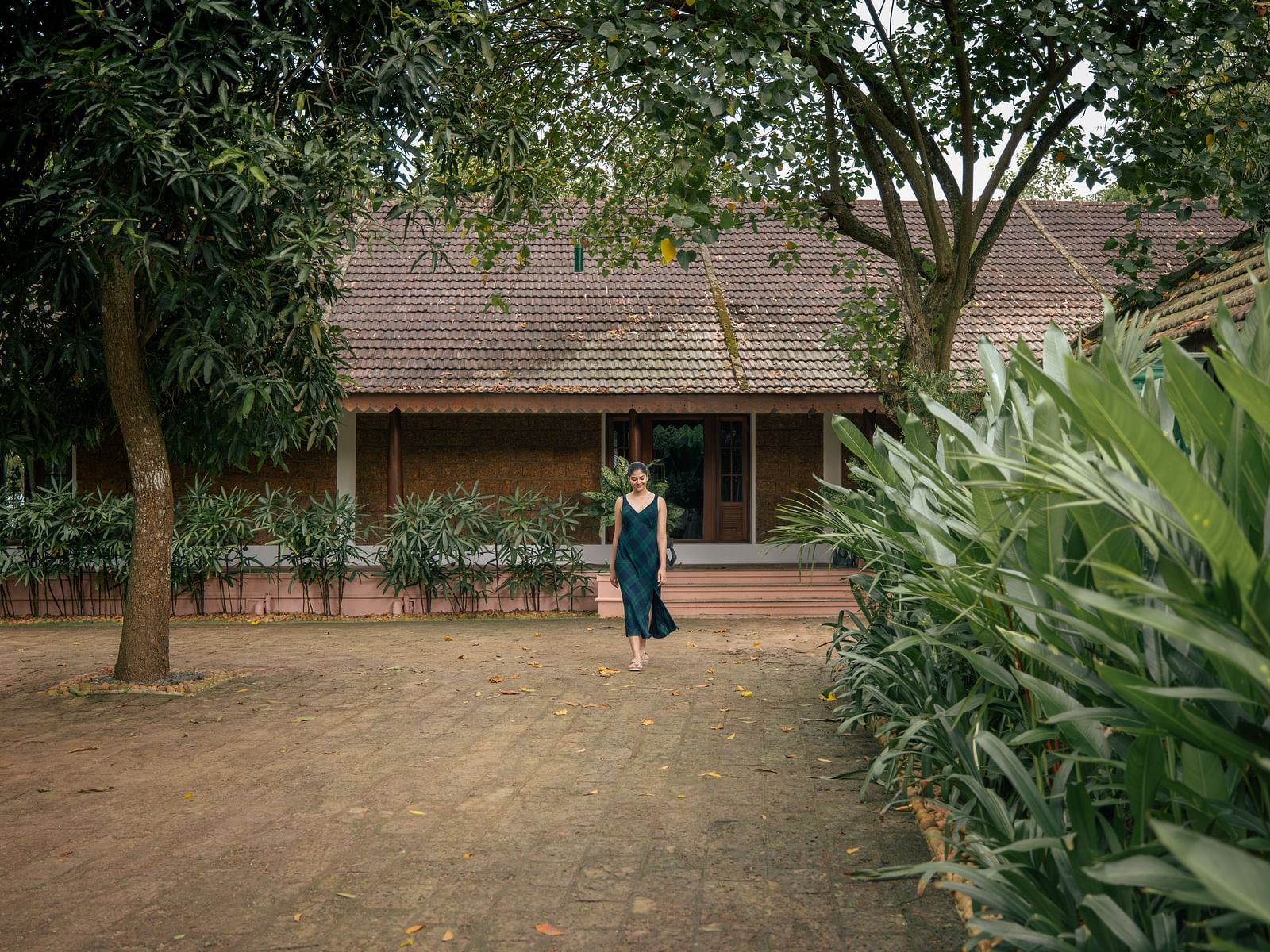 An open area where a woman is seen walking in front of a villa which is surrounded by greenery - BluSalzz Villas - Muhamma Resort, Alleppey