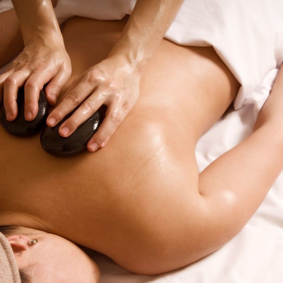 A person getting a hot stone massage while lying on her stomach at YO1 Longevity & Health Resort