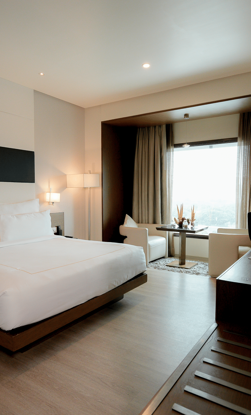 Spacious hotel room with minimalist decor at Narayani Heights Hotel & Resorts, Ahmedabad.