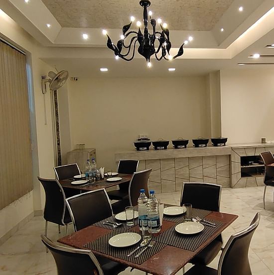 A dining room with set tables and chairs - Asian Suites Cyber Park, Gurgaon.