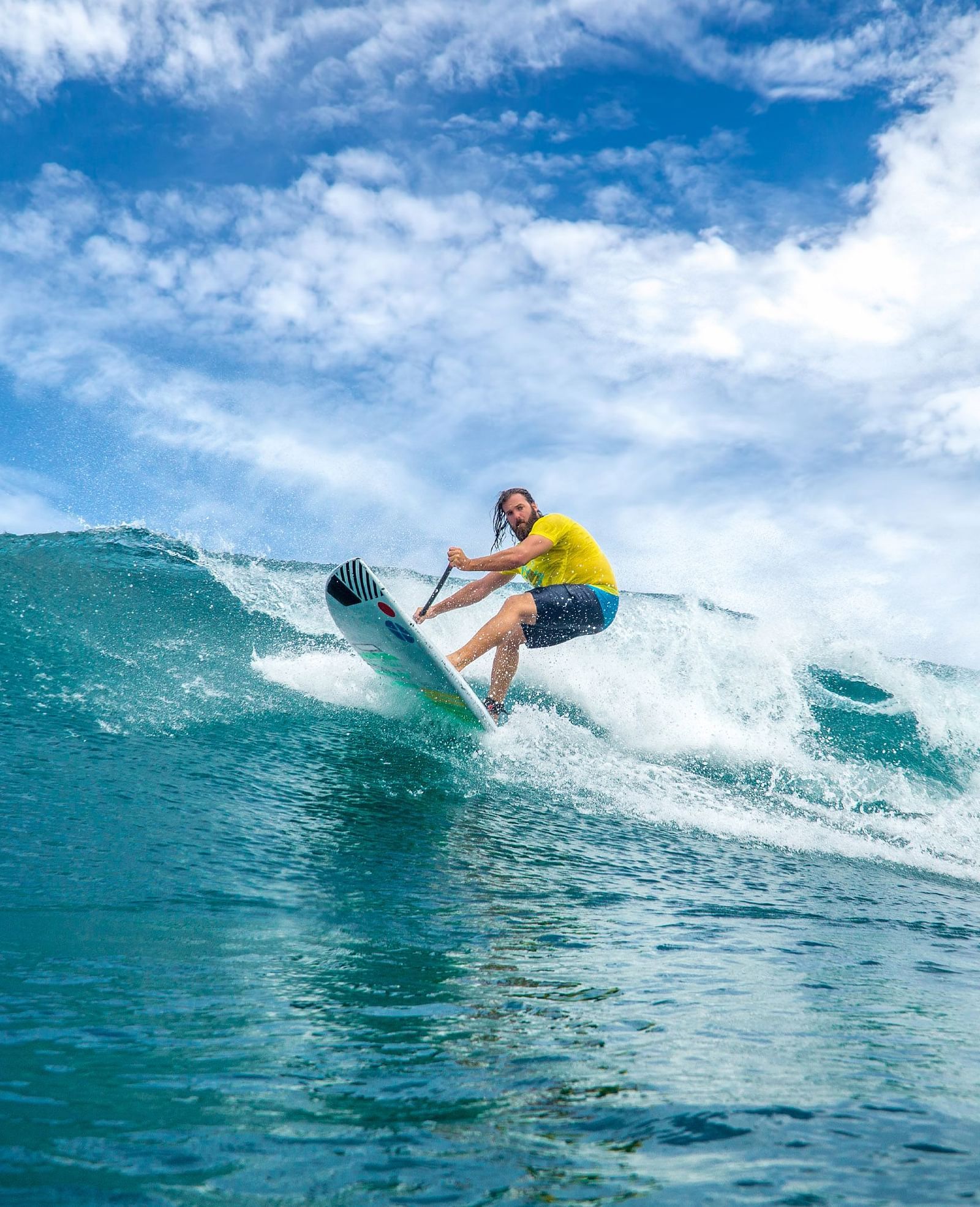 A surfer riding a powerful ocean wave, leaning forward on the surfboard while maintaining balance against the rushing water | Abaco Inn