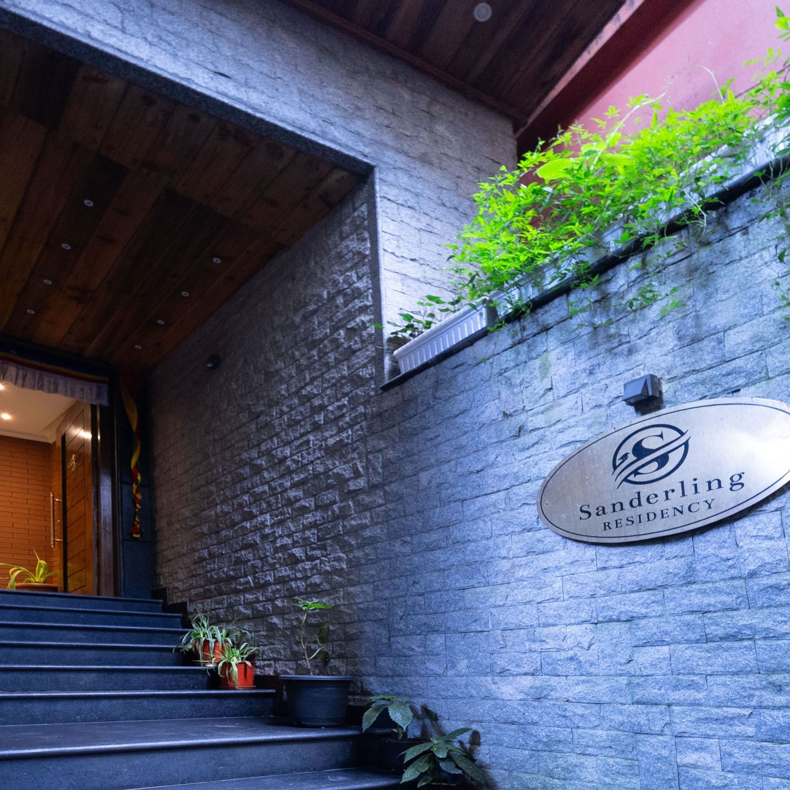 Entrance view of Sumitel Premier Inn, Siliguri, with a stone wall, greenery, and the property’s nameplate creating a warm and inviting arrival experience.