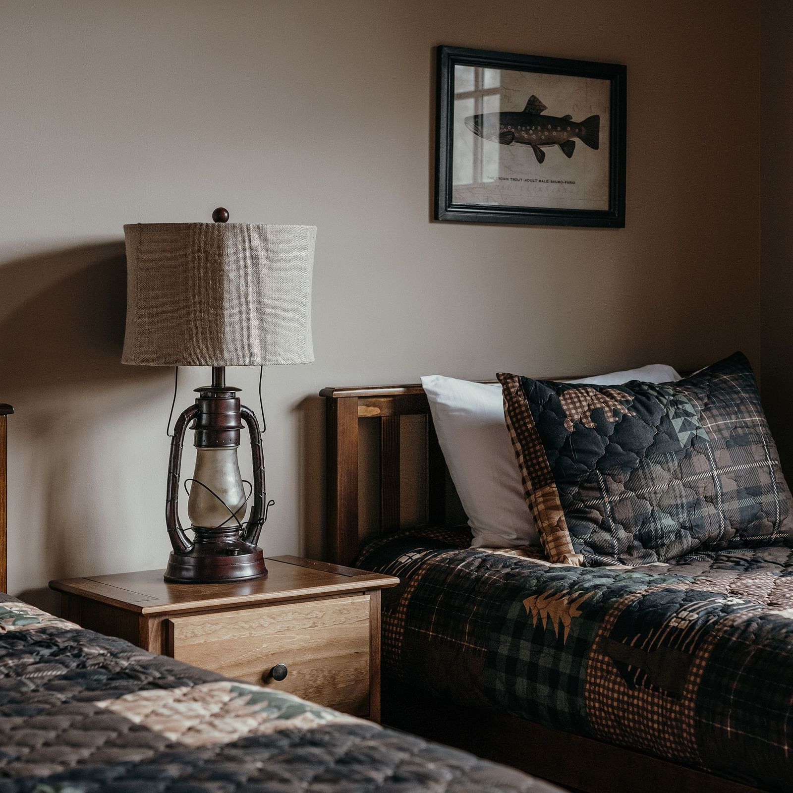 Twin beds with a lamp and side table in between inside a hotel