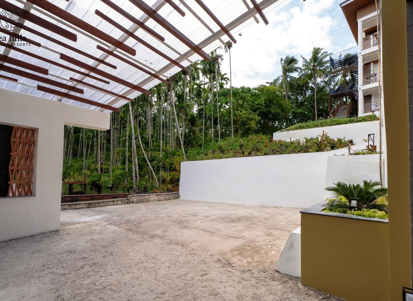 A modern outdoor patio area with a slatted roof and white walls, surrounded by trees. - Sea Hills Resort, Swaraj Dweep (Havelock)