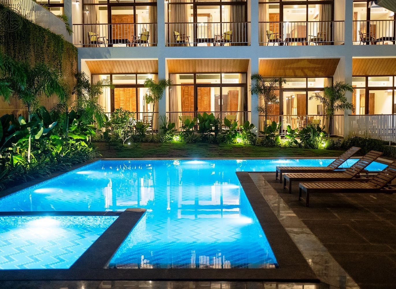 An exterior view of a hotel building with a brightly lit swimming pool in the foreground at dusk. - Sea Hills Resort, Swaraj Dweep (Havelock)