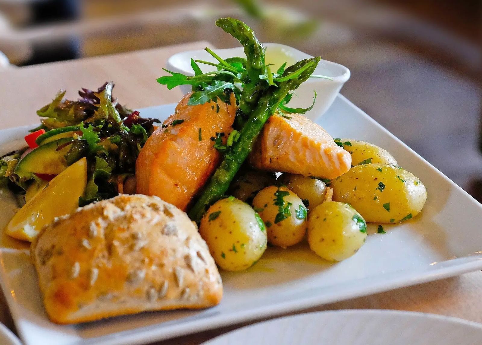 A plate with a main course including roasted vegetables, a bread roll, and a side salad | Altamont Court, Jamaica